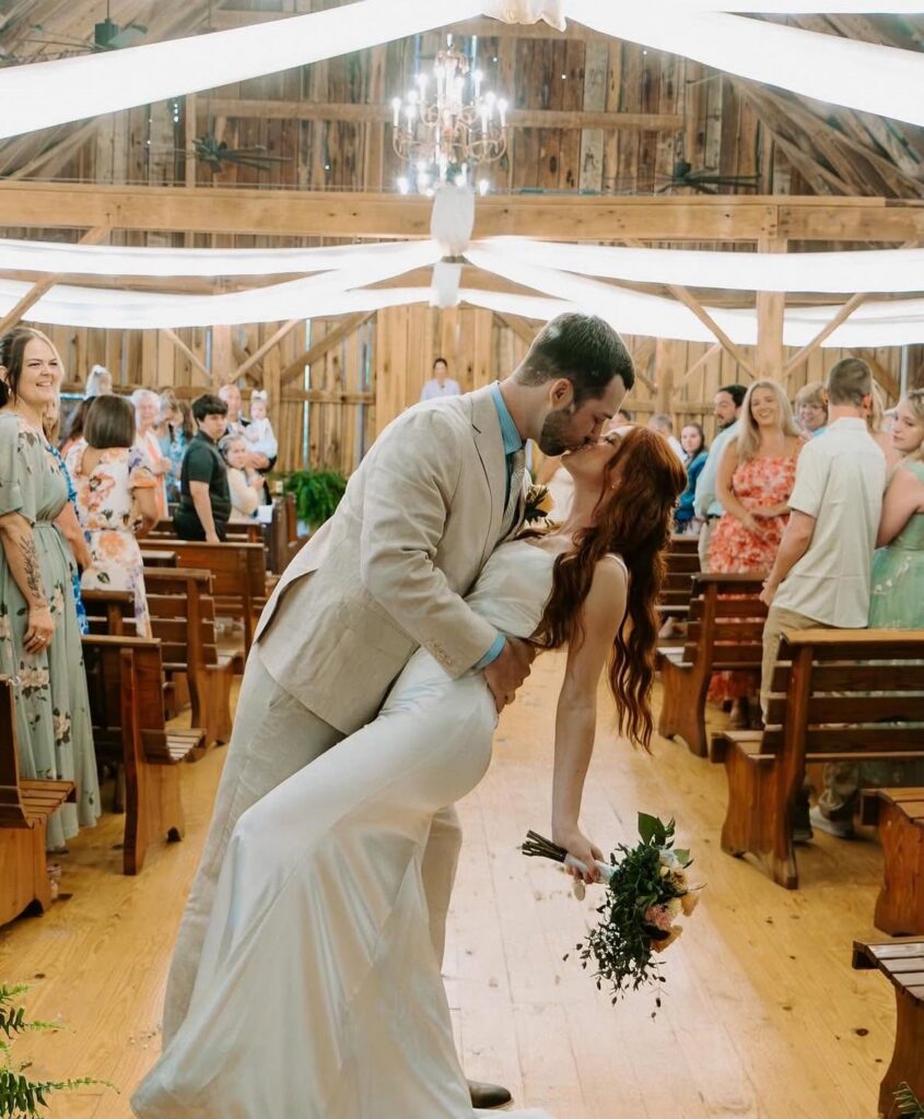 Newlyweds kissing in the aisle as guests cheer