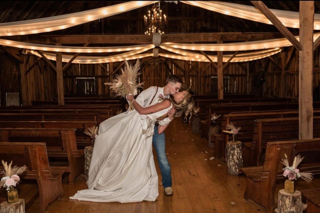 Couple sharing a dip kiss in the barn aisle