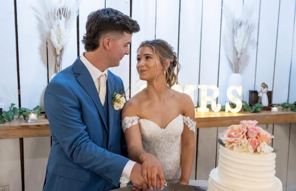 Couple at their reception beside the wedding cake