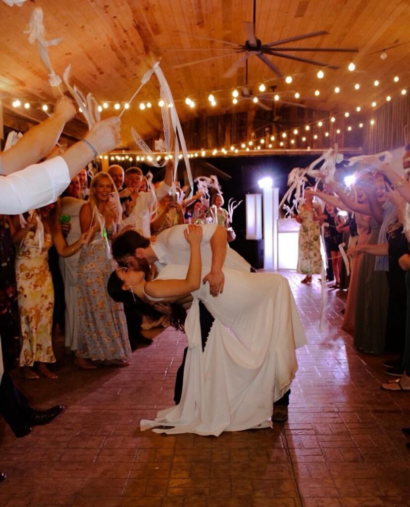 Wedding guests celebrating under string lights in the barn